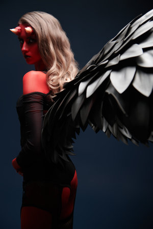 Fantasy heroes. Halloween. An attractive she-devil with bloody horns and black wings on a black...