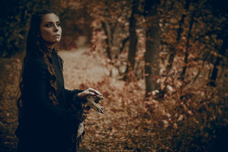 Shamanic rituals. A shaman woman in black garment with ethnic ornaments on her face performs a...