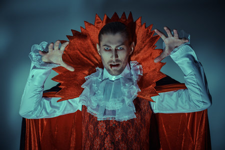 Portrait of a vampire. The 19th century style vampire man viciously raises his arms going to attack his victim. Old movie style. Halloween.の写真素材