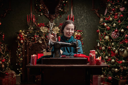 A seamstress in a magical Christmas setting. A beautiful lady of the 19th - early 20th century sits at a sewing machine. Magical vintage Christmas.の写真素材