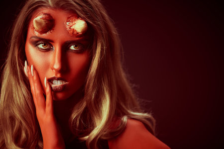 Halloween. A seductive she-devil with bloody horns stands surrounded by hellfire on a black...