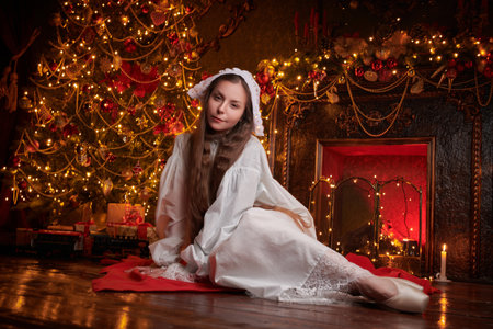 The heroine of the novel of the 19th - early 20th century. An aristocratic lady sits on the floor next to a Christmas tree and fireplace decorated for the holiday. Vintage Christmas.の写真素材