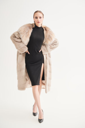 Winter Fashion. Full-length portrait of a gorgeous woman fashion model posing in an expensive mink and fox fur coat on a white studio background. Luxury lifestyle.の写真素材