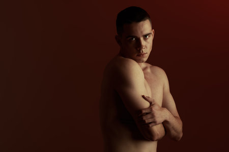 Male beauty and healthcare. Art portrait in a dark key of a handsome young man with an athletic build. Studio shot on a black background with copy-space.の写真素材