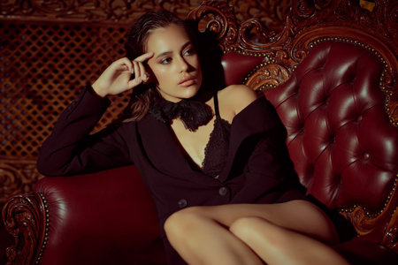 Beautiful sexy lady in black lace lingerie and a jacket is alluring on a vintage armchair. Luxurious...