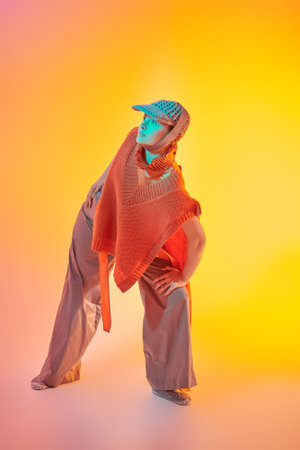Designer knitwear collection. Stylish fashion model posing in wide leg trousers, knitted poncho and knitted cap in studio in mixed color light. Bright colors. New fashionable demi-season collection.の写真素材