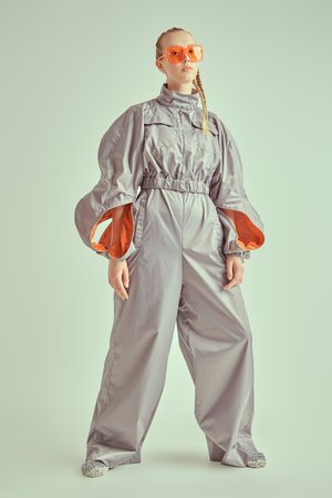 Full length portrait of a beautiful female fashion model posing in a grey pantsuit on a white studio background. High fashion. Futuristic Fashion style.の写真素材