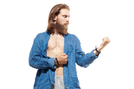 A handsome man with a beard and a medium length haircut in a natural cotton blue shirt on a white studio background is in his thoughts. People, feelings and emotions. Space for text.の写真素材