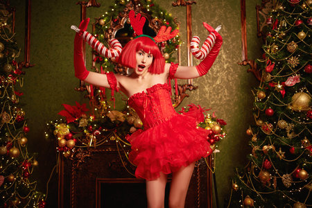 Christmas and New Year celebration. A pretty Asian girl dressed in sexual red dress and a red wig...