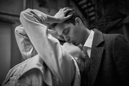 Love story. Young people and relationships. Happy young couple in love kissing each other while standing on the city street. Walk on a cloudy day. Black-and-white shot.の写真素材