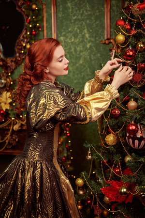 Christmas stories. Beautiful kind princess girl with curly red hair decorates the Christmas trees for Christmas in her castle.の写真素材