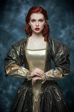 Fairy princess. Lovely tender red-haired girl with beautiful blue eyes in a brown and gold ball gown on a vintage background.の写真素材
