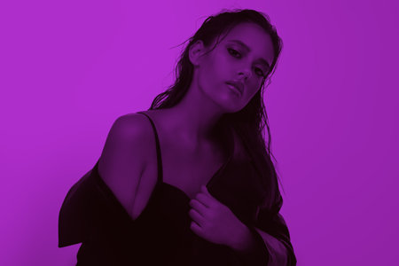 Beauty of women. Portrait of an attractive brunette girl posing in black dress and a blazer on a fuchsia background. Copy-space.の写真素材