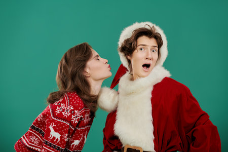 Merry Christmas! Happy New Year! Two cute emotional teenagers - a girl and a boy - dressed in New Year's costumes. Green studio background.の写真素材