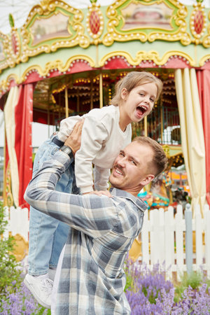 A little girl is in an amusement park with her father. Summer holidays and vacation. Happy family.の写真素材