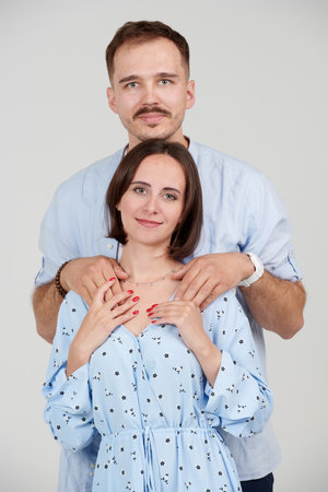 A happy family. A handsome young man hugs his beloved young woman. Married couple. Studio portrait with white backgroud.の写真素材