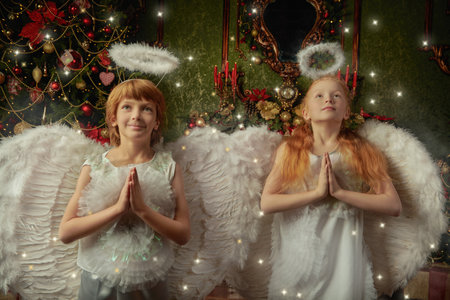 Two little kids dressed as angels  stand in a beautiful Christmas setting and pray. Merry Christmas and Happy New Year! Vintage style.の写真素材