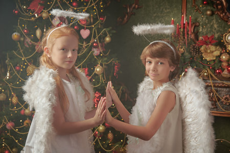 Two little kids dressed as angels  stand in a beautiful Christmas setting. Merry Christmas and Happy New Year! Vintage style.の写真素材