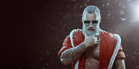 A handsome brutal muscular Santa Claus in a red fur coat and sunglasses stands covered in snow and looks at the camera. Black background with snowfall. Place for text. Christmas and New Year.の写真素材