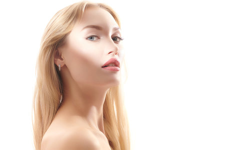 Portrait of a beautiful sensual young woman with blonde hair and natural makeup posing with bare shoulders on a white studio background. Beauty care cosmetics. Cosmetology. Copy space.の写真素材