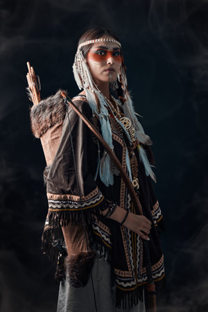 A beautiful American Indian girl in traditional dress and jewelry on a black background.の写真素材
