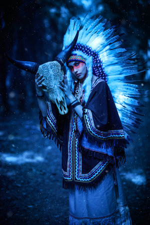 An American Indian shaman stands in the forest with an animal skull in her hands, calling on its spirit. Portrait in retro style. Moonlight.の写真素材
