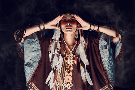 American ethnic culture, history. Portrait of a beautiful American Indian girl in traditional dress and jewelry on a black background.の写真素材