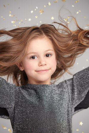 Children's holiday mood. Portrait of a cute little girl smiling cheerfully at the camera on a festive background with gold stars.の写真素材