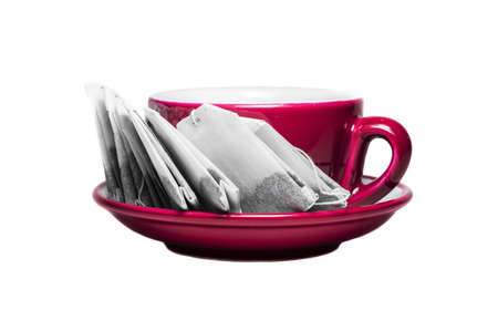Teabags in plate along with the cup of red colors. Objects isolated on white backgroundの写真素材