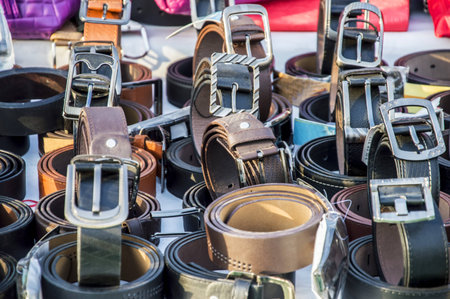 Leather belts of various materials and colors on sale at an open shop.