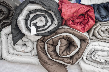 Rolled quilts and blankets of different colors.