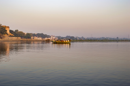 Boat with people crossing river during early morning.の写真素材