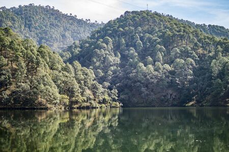 Low water surface of lake in the hills and green reflectionの写真素材