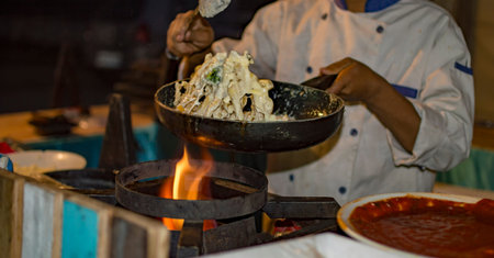 Preparing pasta with white cream in frying pan on flames of fire