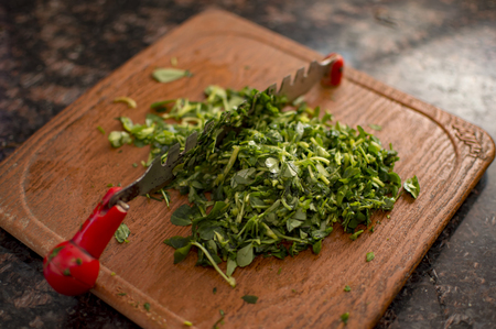 Chopping green leaves of fenugreek on board in kitchenの写真素材