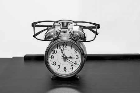 Eye glasses and and an alarm clock on white behindの写真素材