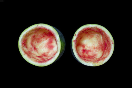 Empty watermelon and two halves on black surfaceの写真素材