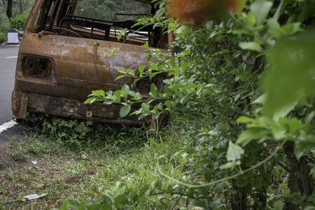 abandoned rust van parked in side of hill road in a foggy bright dayの写真素材