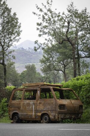 abandoned rust van parked in side of hill road in a foggy bright dayの写真素材