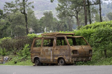 abandoned rust van parked in side of hill road in a foggy bright dayの写真素材