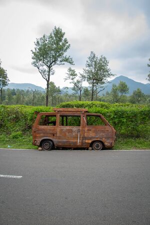 abandoned rust van parked in side of hill road in a foggy bright dayの写真素材