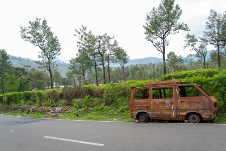 abandoned rust van parked in side of hill road in a foggy bright dayの写真素材