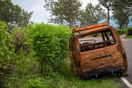 abandoned rust van parked in side of hill road in a foggy bright dayの写真素材