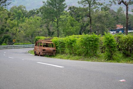 abandoned rust van parked in side of hill road in a foggy bright dayの写真素材