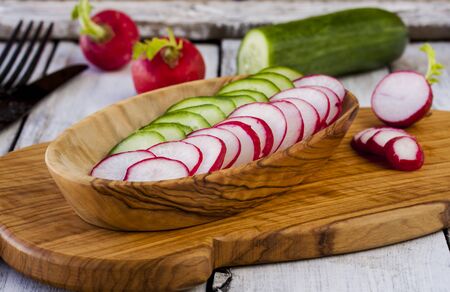 segments of a fresh cucumber and garden radish with a green saladの写真素材