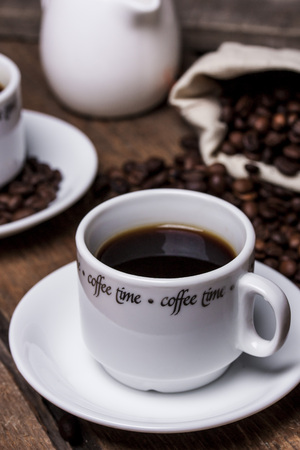 Coffee cup and coffee beans on wooden tableの写真素材