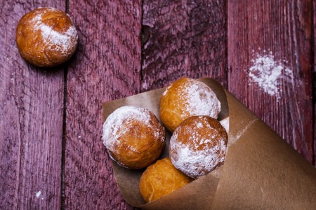 Freshly baked cheese donuts with powdered sugar on a parchment paperの写真素材