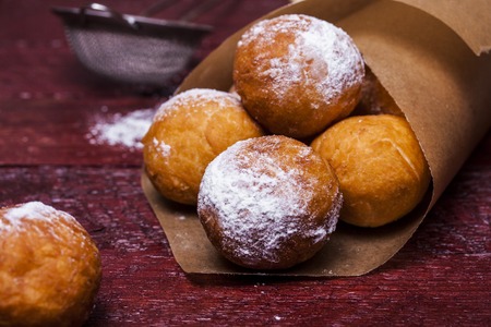 Freshly baked cheese donuts with powdered sugar on a parchment paperの写真素材