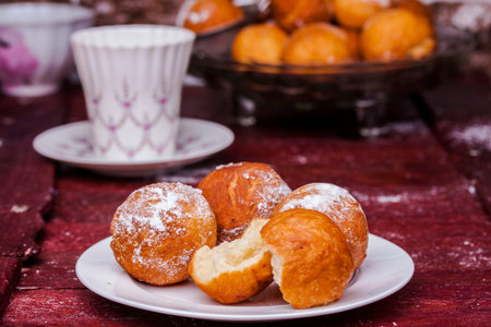 Freshly baked cheese donuts with powdered sugar on a parchment paper