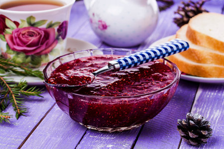 Raspberry jam in a jar on the wooden table